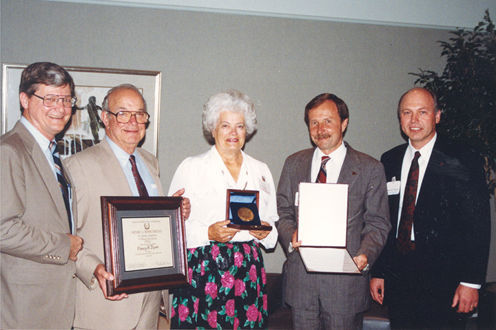 Five people stand holding awards in hands