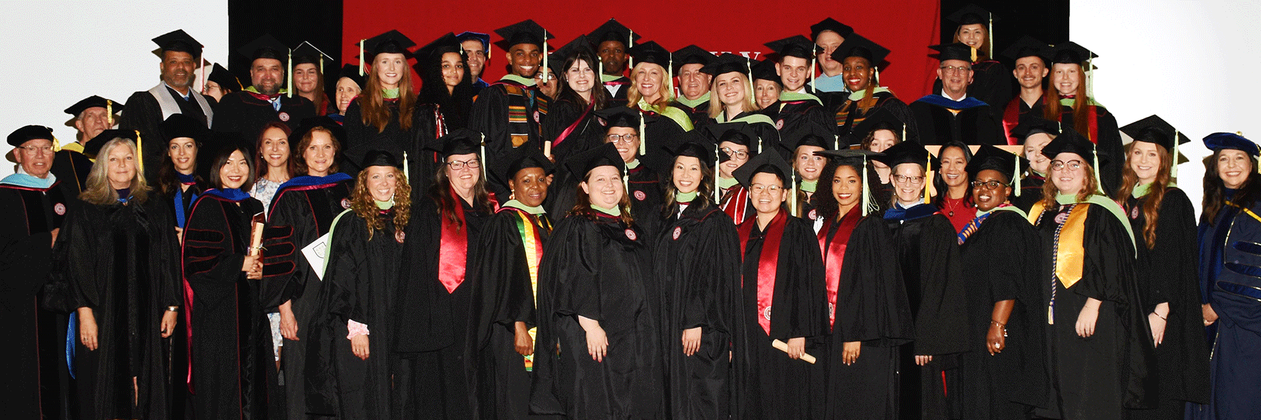 Group of graduates posing for photo in Commencement caps and gowns